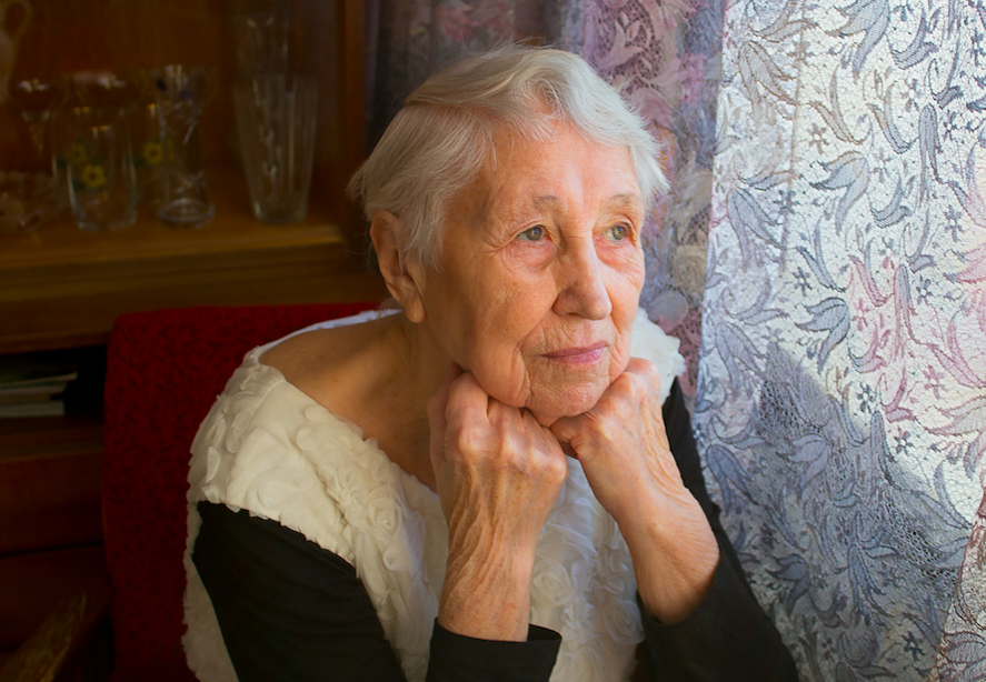 Older adult woman looking out the window