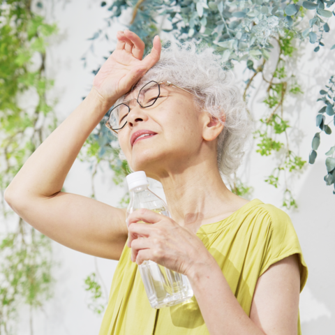 Older adult woman drinking water in the hot sun