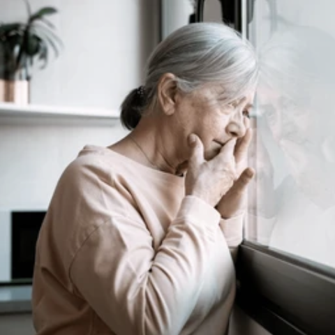 Lonely older adult standing at window