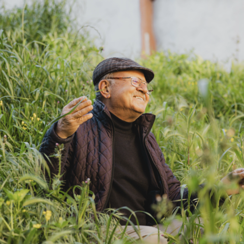 older adult man standing in a field and smiling